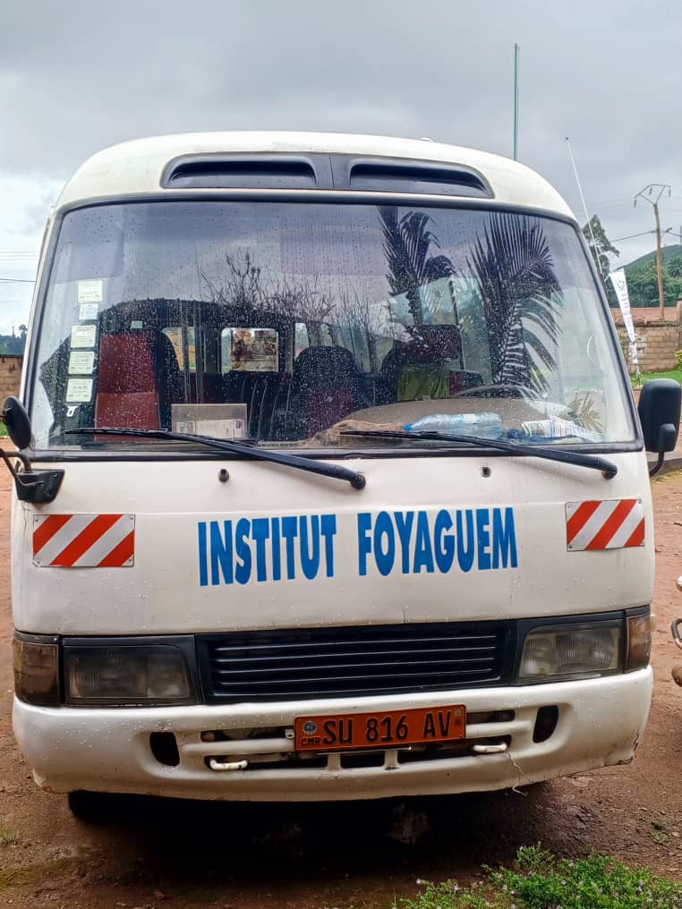 Le bus scolaire blanc de l'institut, lettrage bleu, stationné sur le campus.