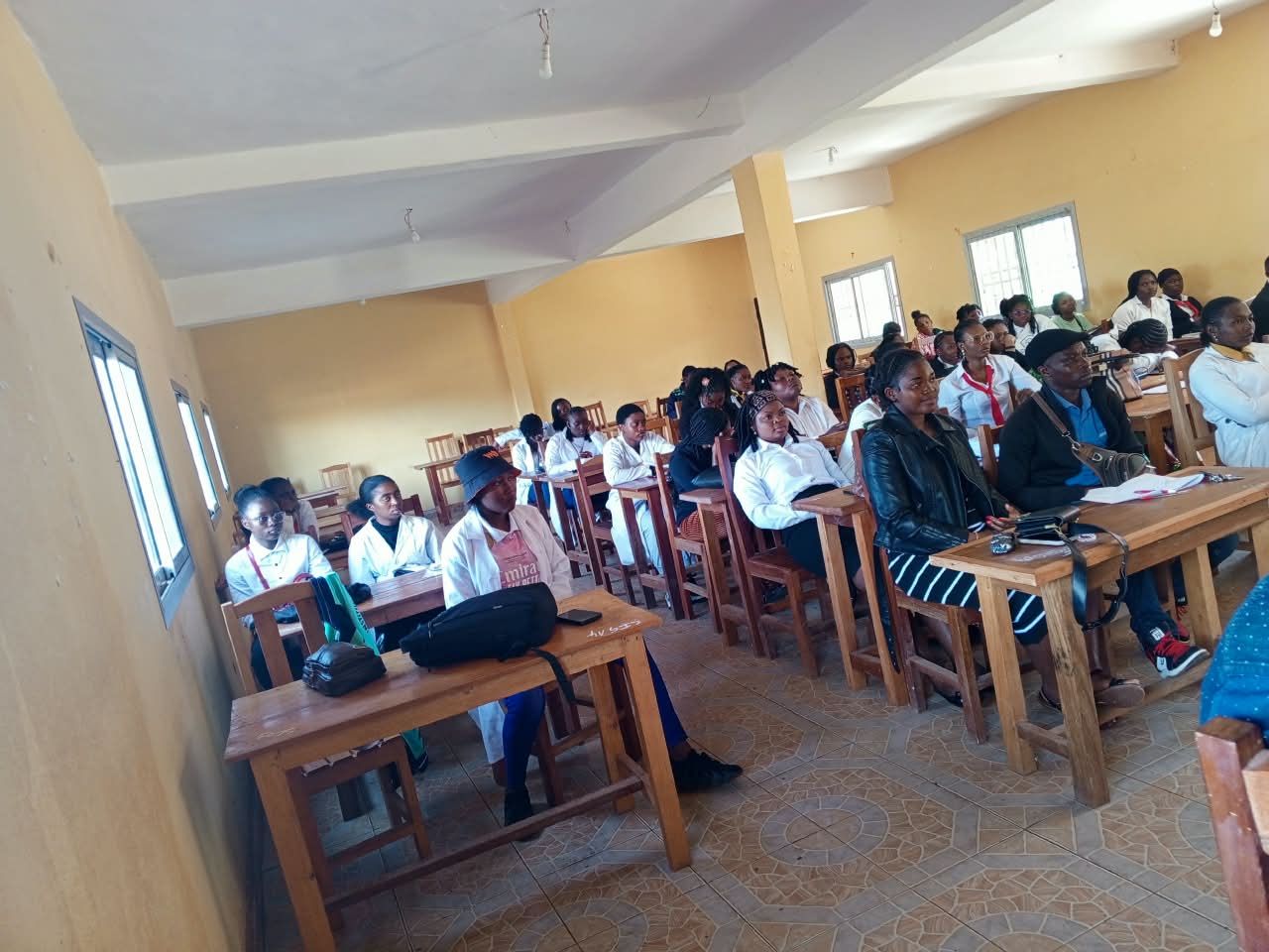 Étudiants en blouse blanche suivant un cours en salle.